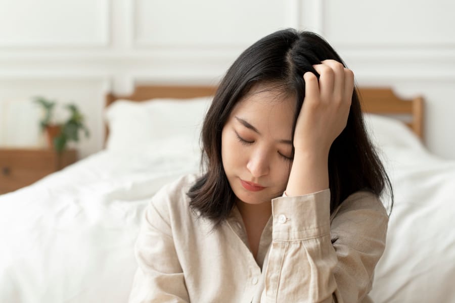 与现实不协调的消耗 与现实不协调的消耗(a woman holding her head in sadness whilst sitting on the corner of her bed)