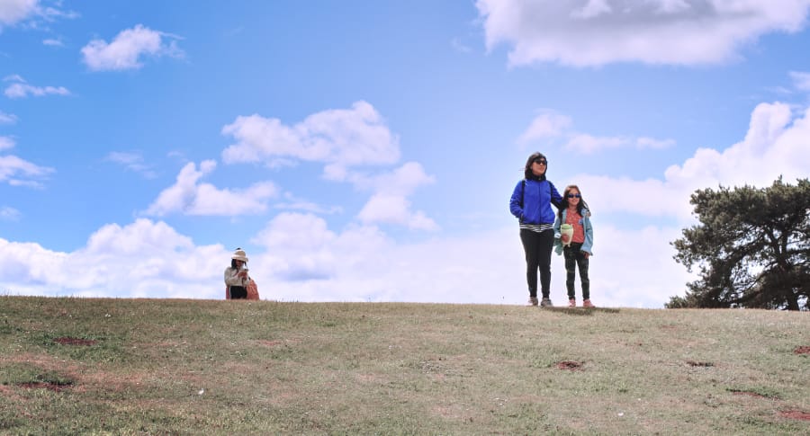 容易被忽略的杯杯面 容易被忽略的杯杯面 (母女俩戴着墨镜站在青翠的山坡上,身旁还有一人,天空湛蓝,白云点缀其间。)