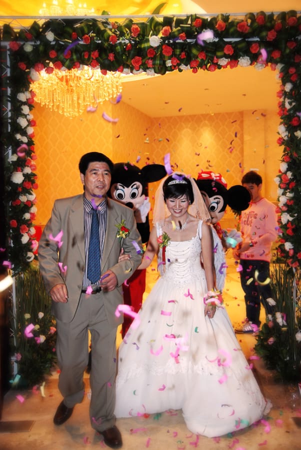 父亲当年送我出嫁的勇气 父亲当年送我出嫁的勇气 (花拱门下,新娘手捧花束,父亲身着卡其色西装,两位米奇玩偶在背后挥手)