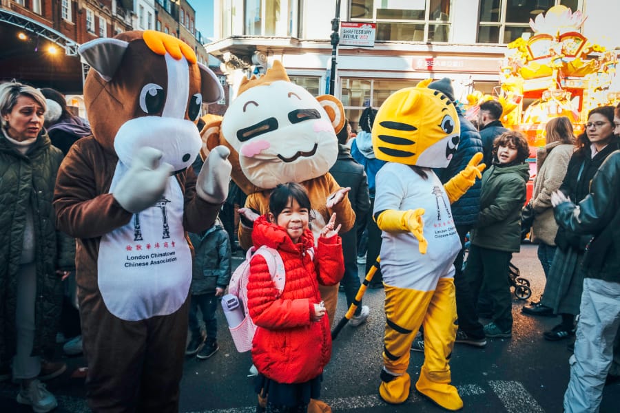 疯猴子在伦敦唐人街农历新年的照片 (伦敦唐人街农历新年庆典中，三位动物吉祥物与观众热情互动，背景为人群与街景)